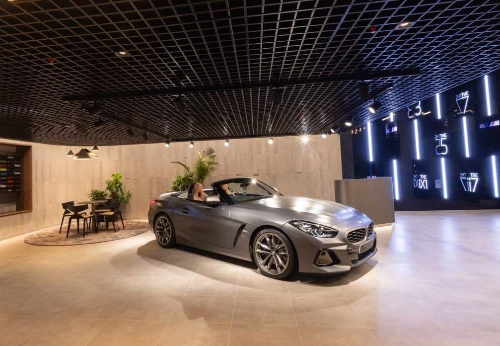 BMW showroom environment with a silver vehicle, timber wall finish and illuminated brand wall